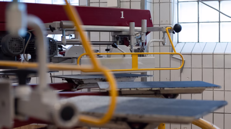 Screentryckmaskin med paletter där textil placeras.